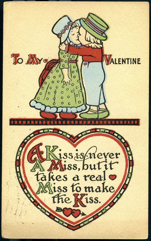 A boy gives a girl a kiss. Text: To my valentine, A kiss is never a miss, but it takes a real miss to make the kiss.