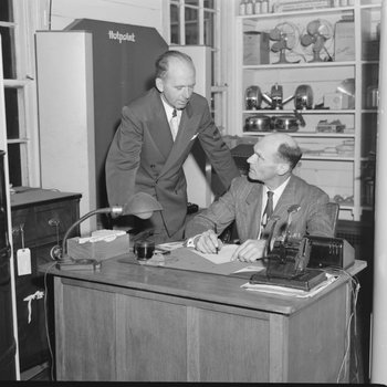 Two men at a desk inside William's Store. Broadway, Va.