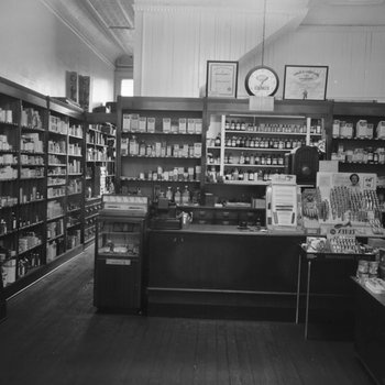 Inside of Everly Drug Store, view of the cash register surrounded by shelves of medicine, hygienic products, beauty products, etc.