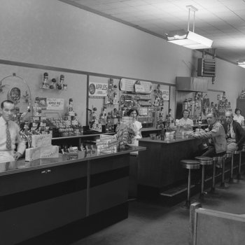 Inside of Walter's Restaurant, with both the counter and opposite booth tables pictured, except with men sitting at the counter.