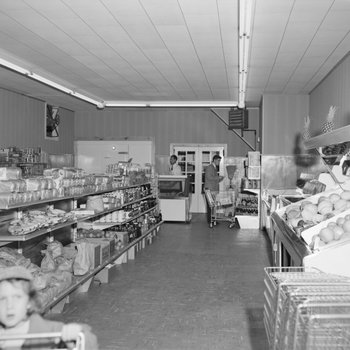 Inside of Mick or Mack "Cash Talks," shelves of food pictured with some shoppers and an employee.