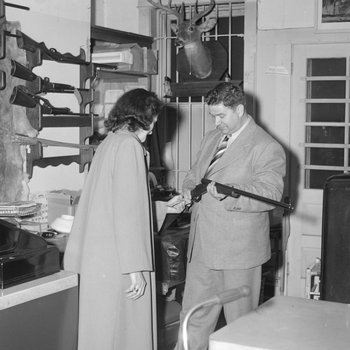Inside Hodgin's Store, a man showing a rifle to a woman. Woodstock, Va.