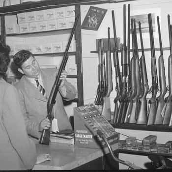 Inside Hodgin's Store, alternate view of a man showing a rifle to a woman. Woodstock, Va.