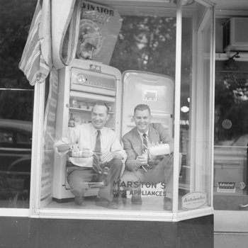 Marston's Home Appliance Store, view of two men pouring drinks in the window display.