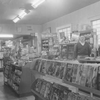 Alternate view of shelving inside of a store or building, with a man pictured.