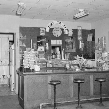 Inside of a diner or store, view of the counter with a door to a kitchen in the background.