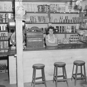 Inside of a store, view of a woman standing behind the counter.