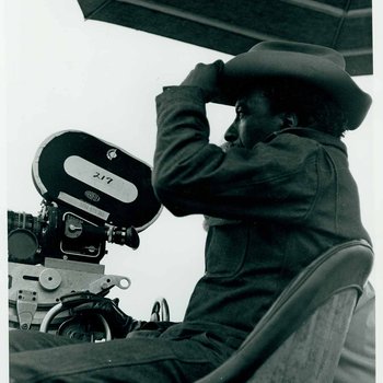 Close up of Gordon Parks sitting behind a movie camera during the filming of "The Learning Tree" on location in Bourbon and Linn counties, Kansas