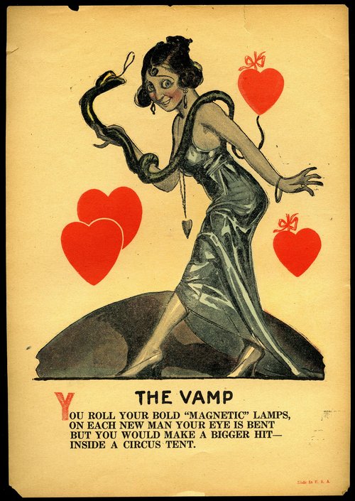 A woman in a long slinky dress holds a snake with hearts floating around her. Text: The Vamp. You roll your bold "magnetic" lamps, on each new man your eye is bent but you would make a bigger hit inside a circus tent.