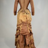 Dress, brown and tan silk taffeta with cuirass bodice and bustle, c. 1883, back view