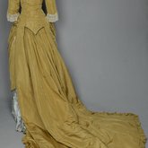 Dress, deep yellow silk taffeta with blue silk satin pleats and long train,1877-1882, back view with restored seams and darts