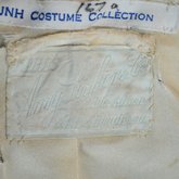 Suit, green wool with braid and velvet, c. 1906, detail of label