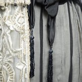 Dress, cream satin with black chiffon overlay and tasseled, embroidered panels, c. 1910s (refurbished), detail of sash