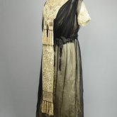 Dress, cream satin with black chiffon overlay and tasseled, embroidered panels, c. 1910s (refurbished), quarter view