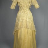 Evening gown, pale yellow faille with Chantilly lace and a bobbinet overlay appliquéd with Art Nouveau lilies, c. 1905, back view