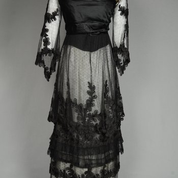 Dress, black silk satin and point d’esprit bobbinet with organdy and cord appliqué, c. 1915-1918, front view