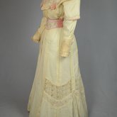Dress, cream wool trimmed with lace, pink velvet, and multi-colored machine embroidery, 1908, quarter view