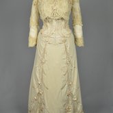 Dress, House of Rouff, cream wool with lace-draped bodice and sleeves, trimmed with cording, ribbon fronds, and roses, c. 1905, front view