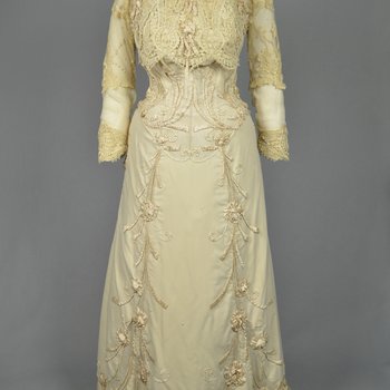 Dress, House of Rouff, cream wool with lace-draped bodice and sleeves, trimmed with cording, ribbon fronds, and roses, c. 1905, front view