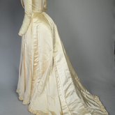 Wedding dress, cream silk satin and lace with long sleeves and a train, c. 1905, quarter view