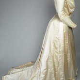Wedding dress, cream silk satin and lace with long sleeves and a train, c. 1905, side view