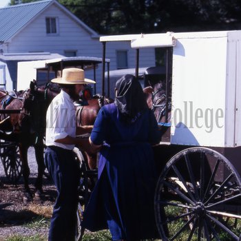 Amish man and woman with white top buggy