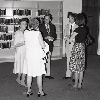 A group of men and women at an event in the library reading room.