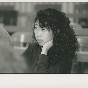 Portrait of female student and listening at table in library.