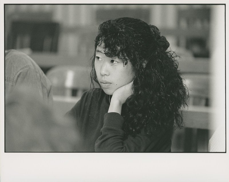 Portrait of female student and listening at table in library.