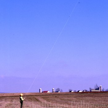 Amish boy flying kite in field