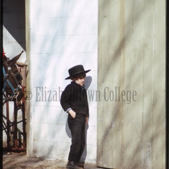 Amish boy leaning against wall