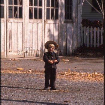 Young boy standing in front of stables