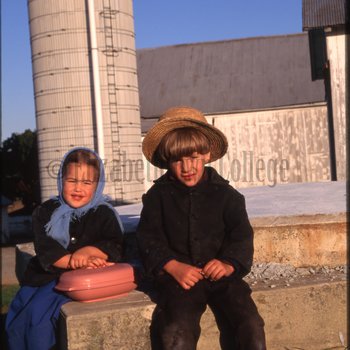 Children sit near barn