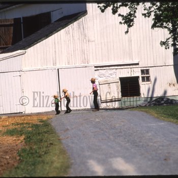 Children play outside barn