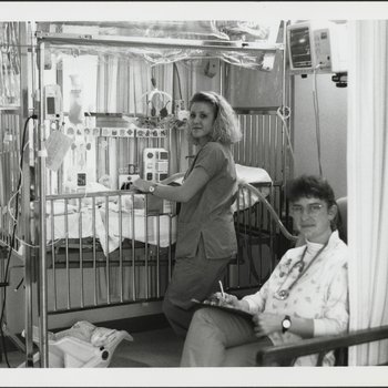 Two Nurses Caring for Patient in Hospital Ward