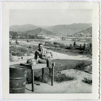 David F. Brock sitting on washstand at Hook base camp