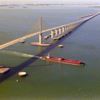 Tugboat Dixie Commander Pushing a Dredge under the Sunshine Skyway Bridge, A