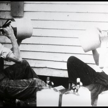 Charlie Reecer and Dewey Smith sampling a batch of moonshine, Clay County, Tennessee, ca. 1920-1925