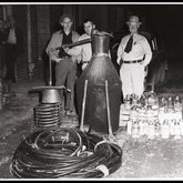 Sheriff Mike Bootright and deputies with a confiscated moonshine still, Elizabethton, Tennessee, ca. 1940s