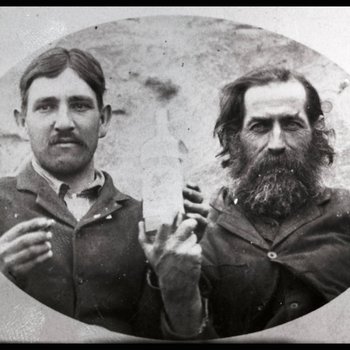 Bud Miller and Bob Swann with the first bottle of legal whiskey from the distillery south of the river Dandridge, Tennessee, ca. 1905