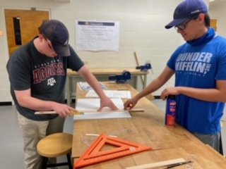 Students Bryant Lee and Jacob Whitehurst cutting foamcore to fit their exhibit items