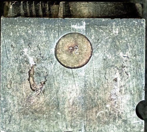 Pin mark stamped into the side of a printing cut, a circle reading "72"