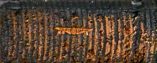 Pin/maker's mark on the side of a printing cut, possibly "TSFU"