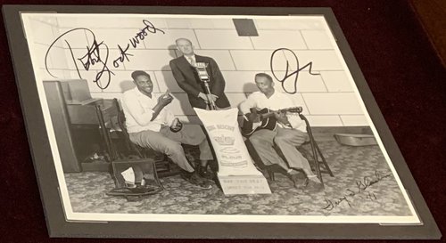 Sonny Boy Williamson, KFFA owner Sam Anderson and Robert Lockwood Jr. pose with a bag of King Biscuit flour. "Ivey S. Gladdin &#x27;41" is in bottom right corner. Signed by Robert Lockwood, Jr.