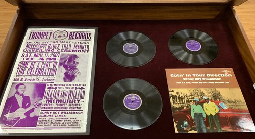 Display case features 3 78s, 1 LP, and one poster. Contents are itemized in the text.