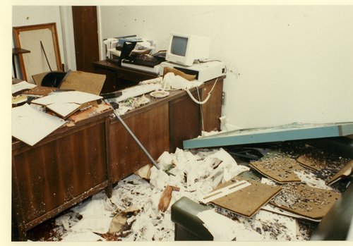 Interior image of office damaged in by Hurricane Hugo. A mass of wet papers and debris from partially fallen in ceiling tiles cover the floor.