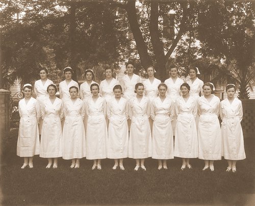 Sepia toned group portrait of eighteen young women in all white nursing uniform from 1934.