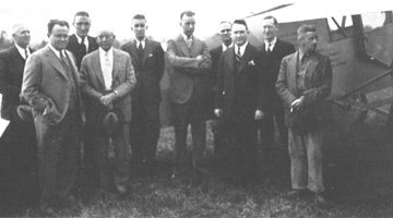 photo of William Faulkner in front of an airplane with a group of local men, 1936