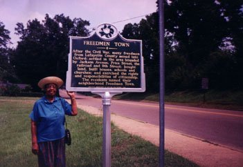 Mrs. Susie Marshall at the Historic sign for Freedmen Town, Oxford, Mississippi, 1995