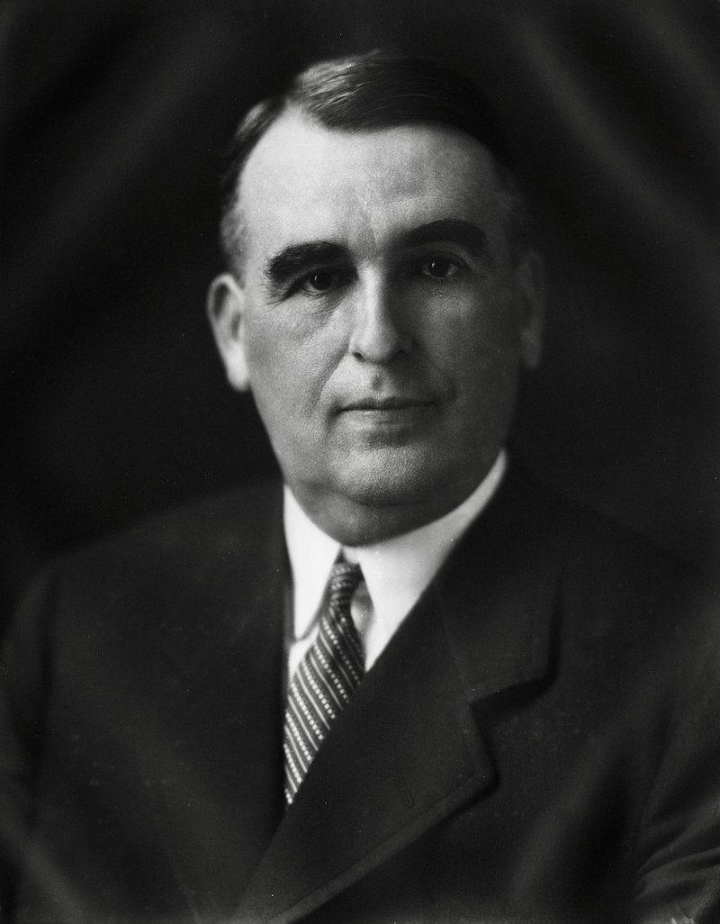 Hugh L. White, Governor of Mississippi, sits posed for a photograph. He is an older white man with a comb-over haircut and is wearing a suit and tie.